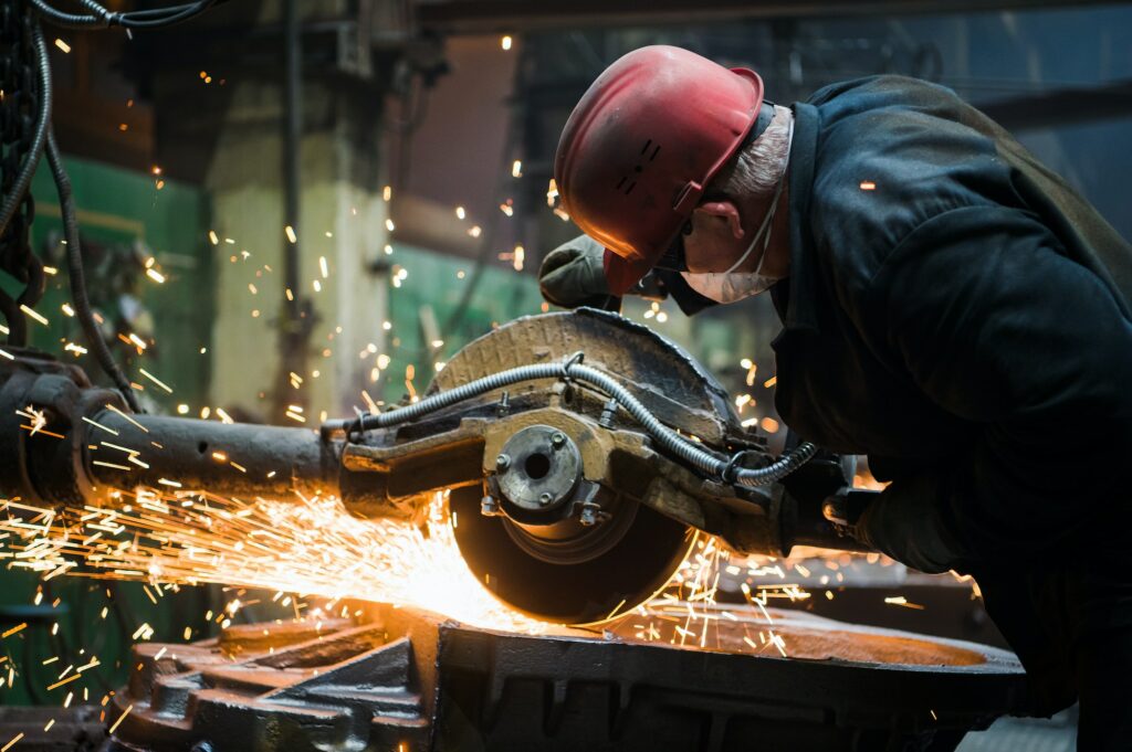 Worker grinding metal, metal grinding machine with sparks, metal sawing
